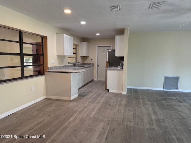 kitchen with stainless steel refrigerator, sink, white cabinets, and hardwood / wood-style floors