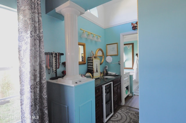 bathroom featuring decorative columns, wine cooler, hardwood / wood-style floors, and vanity