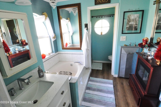 bathroom featuring hardwood / wood-style flooring, vanity, toilet, and tiled tub