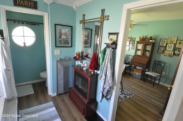 interior space with hardwood / wood-style floors, toilet, ceiling fan, and ornamental molding