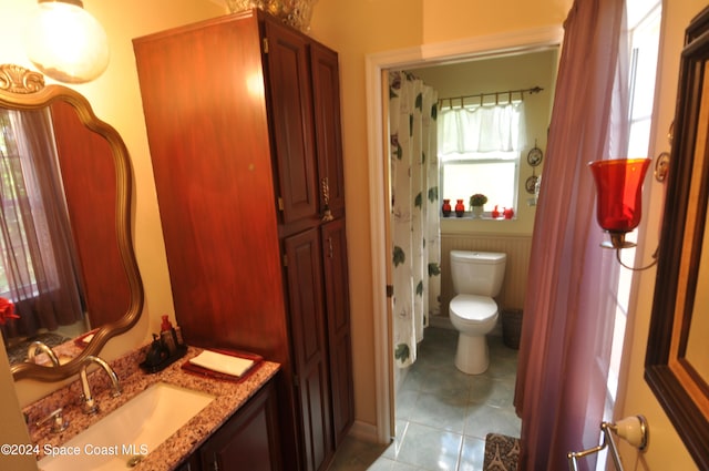 bathroom featuring toilet, vanity, tile patterned floors, and a wealth of natural light