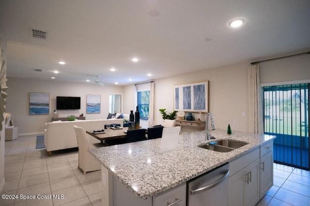 kitchen with sink, light tile patterned floors, stainless steel dishwasher, and a center island with sink