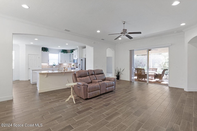 living room featuring ceiling fan, dark hardwood / wood-style floors, and ornamental molding