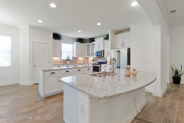 kitchen featuring white cabinets, sink, an island with sink, and appliances with stainless steel finishes