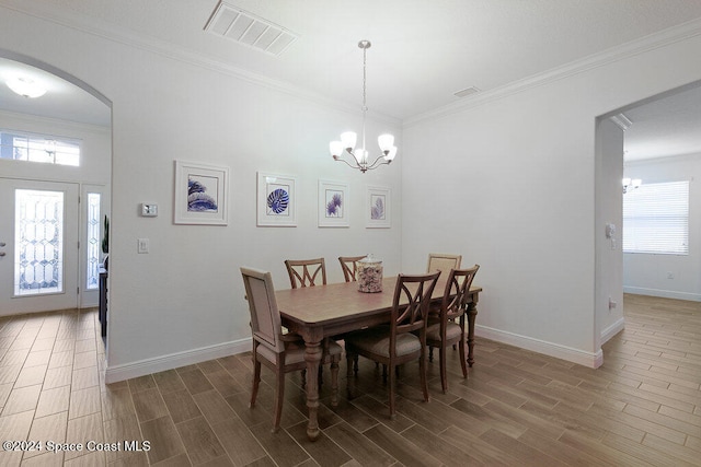 dining area with ornamental molding, a chandelier, and hardwood / wood-style flooring