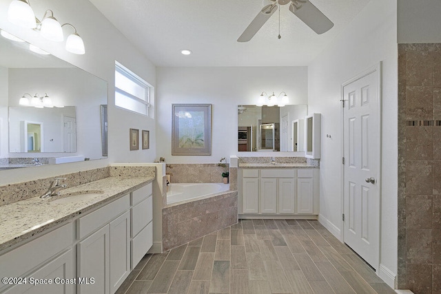 bathroom with hardwood / wood-style floors, vanity, ceiling fan, and tiled bath