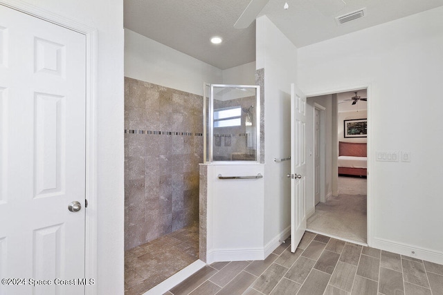 bathroom with a tile shower and ceiling fan