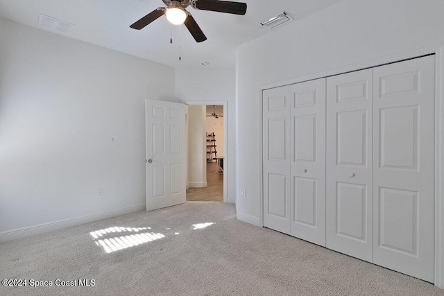 unfurnished bedroom featuring a closet, light colored carpet, and ceiling fan