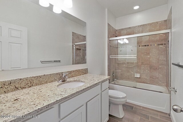 full bathroom with shower / bath combination with glass door, vanity, and toilet