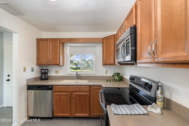 kitchen featuring sink, light tile patterned flooring, stainless steel appliances, and a textured ceiling