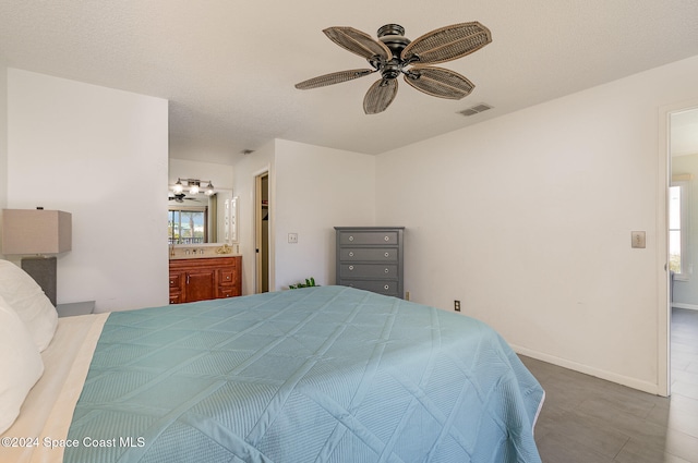 bedroom with ensuite bath, ceiling fan, a textured ceiling, and multiple windows