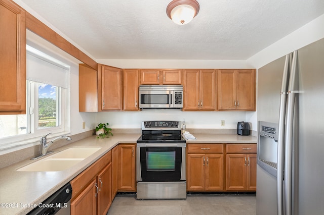 kitchen featuring light tile patterned floors, a textured ceiling, stainless steel appliances, and sink