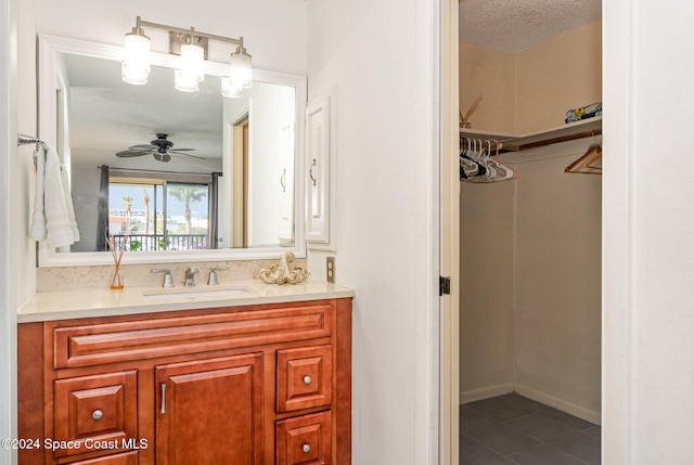 bathroom with a textured ceiling, vanity, and ceiling fan