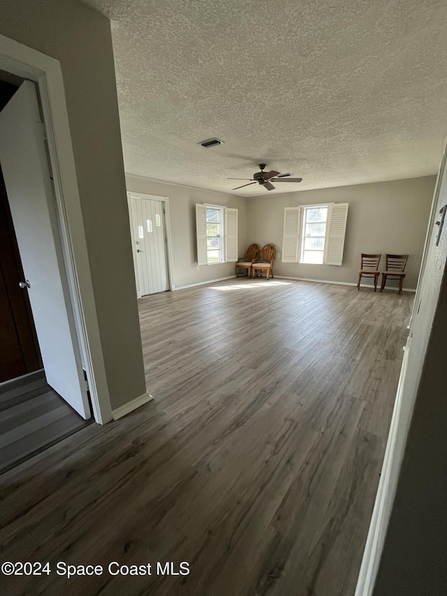 unfurnished living room with ceiling fan, dark hardwood / wood-style flooring, and a textured ceiling