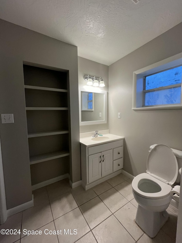 bathroom with tile patterned floors, vanity, a textured ceiling, and built in shelves