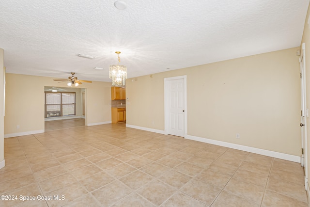 unfurnished room with ceiling fan with notable chandelier, light tile patterned flooring, and a textured ceiling