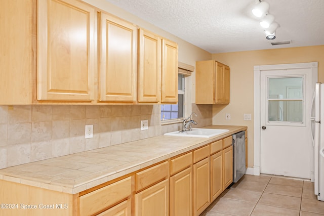 kitchen featuring tile countertops, dishwasher, sink, light tile patterned floors, and light brown cabinetry