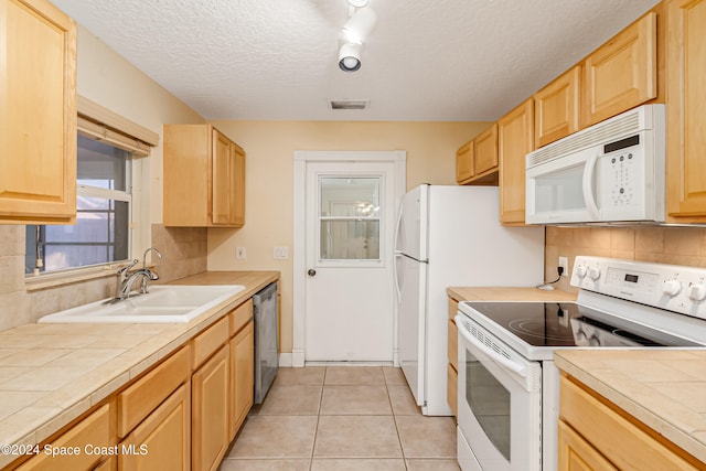 kitchen featuring a textured ceiling, tile counters, white appliances, and sink