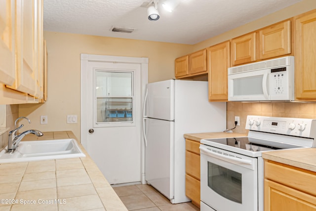 kitchen with light brown cabinetry, white appliances, a textured ceiling, sink, and light tile patterned flooring