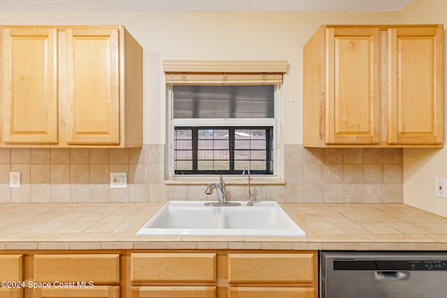 kitchen featuring stainless steel dishwasher, decorative backsplash, light brown cabinets, and sink