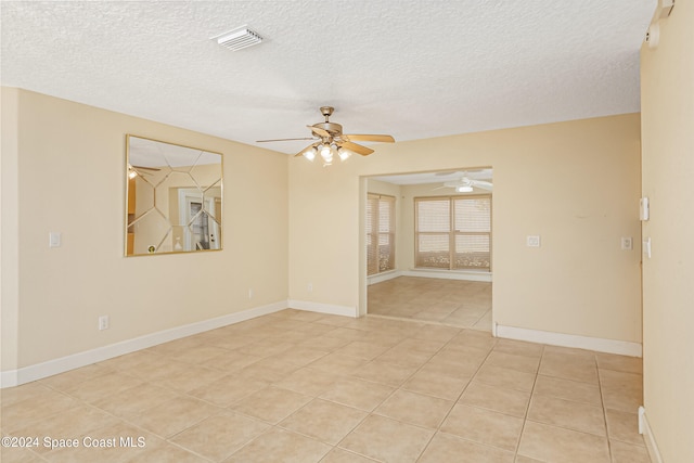 spare room with a textured ceiling, ceiling fan, and light tile patterned flooring