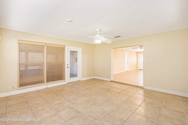 spare room with ceiling fan, light tile patterned floors, and a textured ceiling