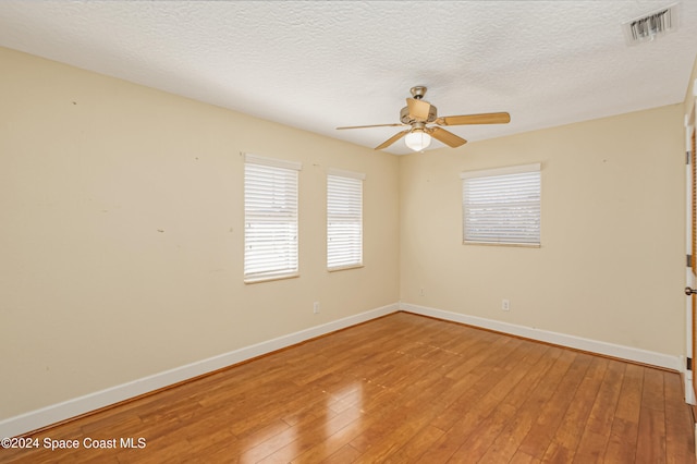 empty room with hardwood / wood-style floors, ceiling fan, and a textured ceiling