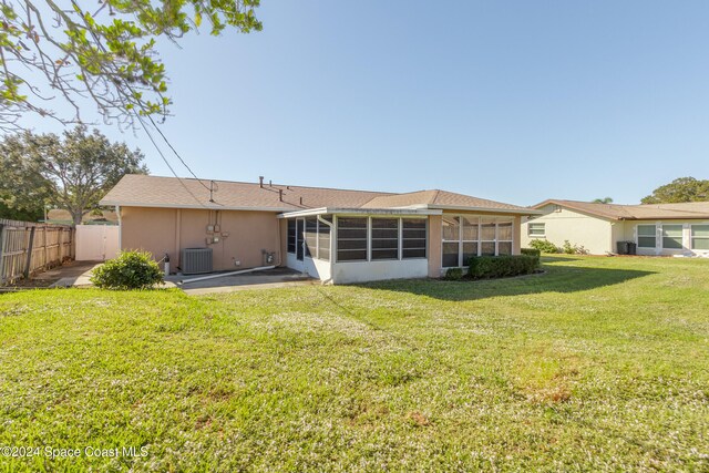 rear view of house with a sunroom, a patio, cooling unit, and a lawn