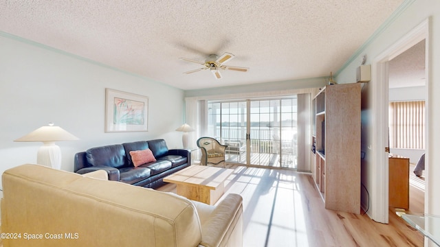 living room featuring ceiling fan, light hardwood / wood-style floors, a textured ceiling, and ornamental molding