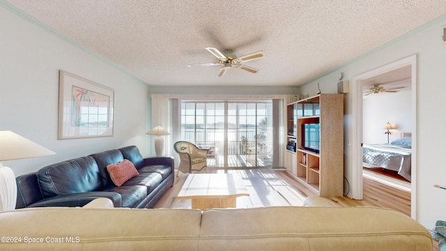 living room featuring ceiling fan, crown molding, light hardwood / wood-style floors, and a textured ceiling