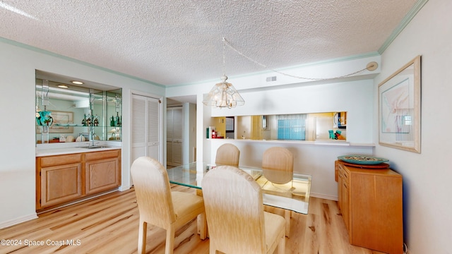 dining room with ornamental molding, a textured ceiling, light hardwood / wood-style floors, and a notable chandelier