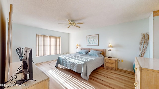 bedroom featuring ceiling fan, light hardwood / wood-style floors, and a textured ceiling