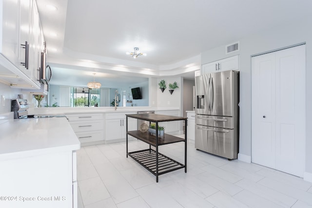 kitchen with white cabinetry, appliances with stainless steel finishes, sink, and a notable chandelier