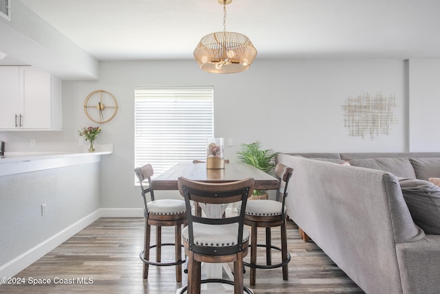 dining space with wood-type flooring and an inviting chandelier