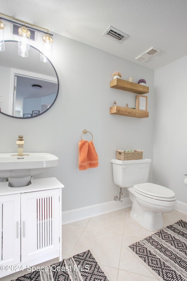 bathroom featuring tile patterned floors, vanity, toilet, and a textured ceiling