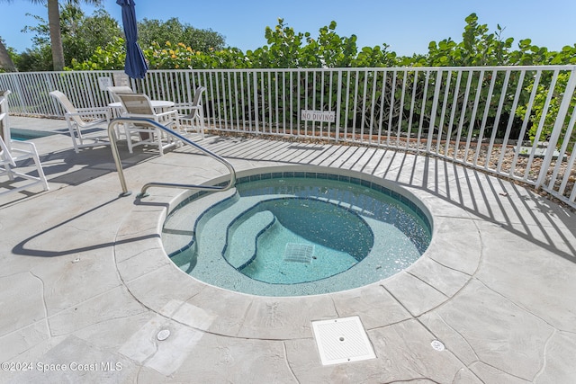 view of swimming pool featuring a hot tub and a patio