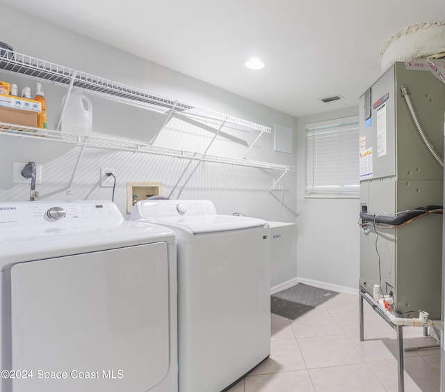 washroom with washer and dryer, light tile patterned flooring, and heating unit