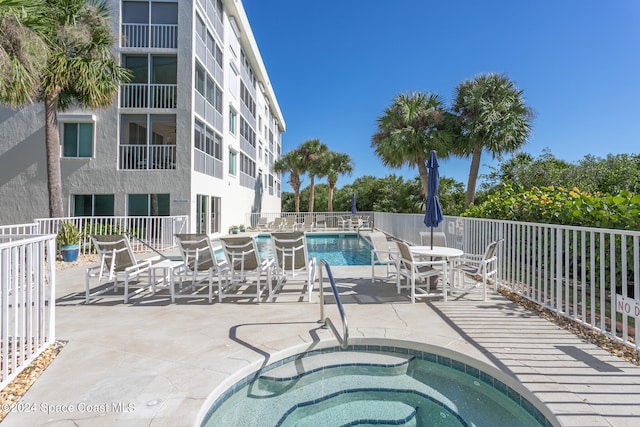 view of swimming pool with a hot tub and a patio