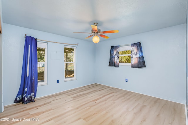 spare room with ceiling fan, plenty of natural light, and light wood-type flooring