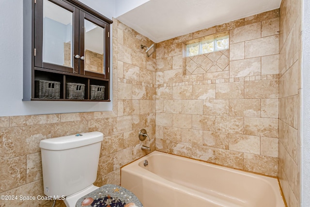 bathroom with toilet, tiled shower / bath combo, and tile walls