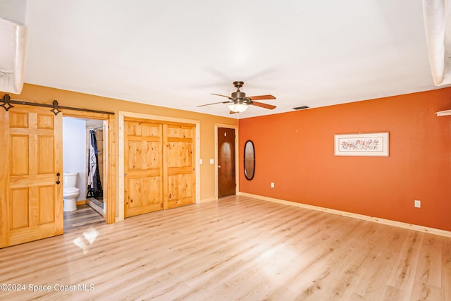 interior space with connected bathroom, hardwood / wood-style floors, a closet, and a barn door