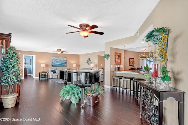 dining area with a textured ceiling, ceiling fan, and dark wood-type flooring