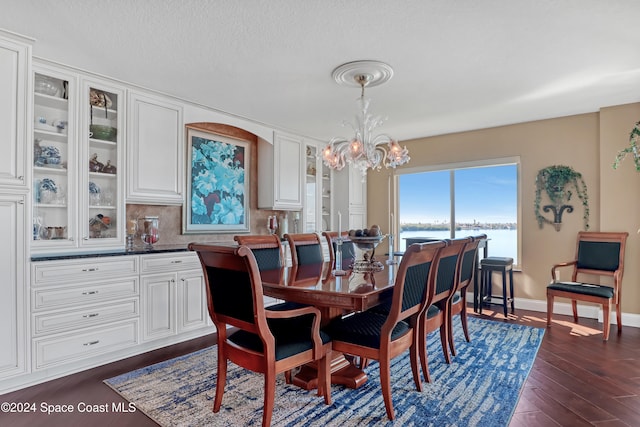 dining room featuring a water view, dark hardwood / wood-style floors, and a notable chandelier