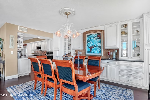 dining space featuring dark hardwood / wood-style floors and an inviting chandelier