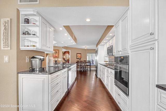 kitchen featuring dark stone countertops, white cabinetry, dark wood-type flooring, and stainless steel appliances