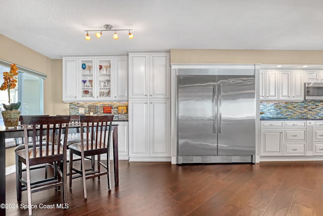 kitchen with appliances with stainless steel finishes, tasteful backsplash, a textured ceiling, dark hardwood / wood-style floors, and white cabinetry