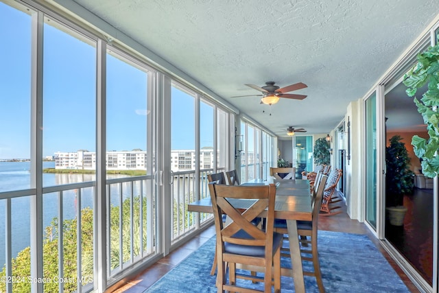 sunroom / solarium with ceiling fan and a water view