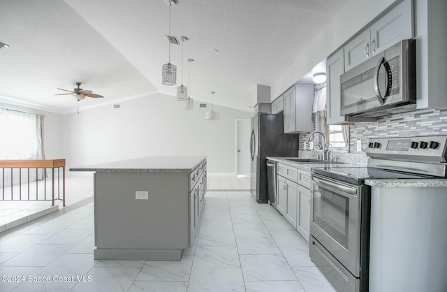 kitchen featuring appliances with stainless steel finishes, ceiling fan, sink, pendant lighting, and a center island