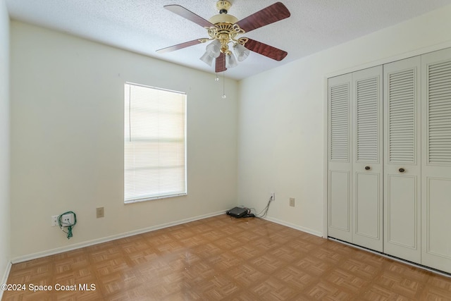 unfurnished bedroom featuring ceiling fan, light parquet floors, a textured ceiling, and a closet