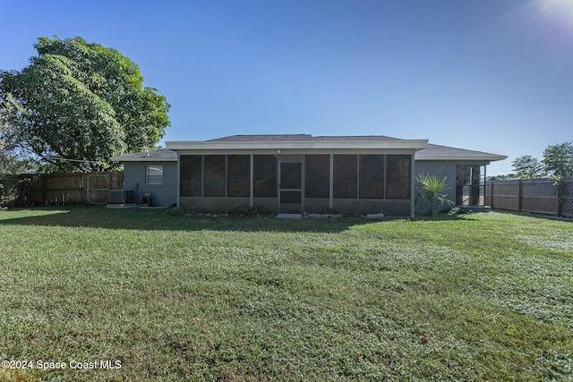 rear view of house with a sunroom, central AC unit, and a lawn